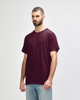 A man wearing a burgundy Gildan Heavy Cotton Adult T-Shirt, standing against a plain background.