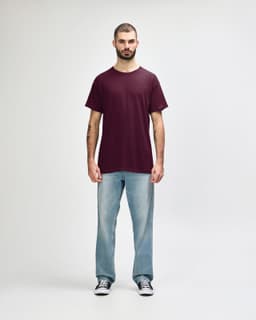 A maroon Gildan Heavy Cotton Adult T-Shirt displayed on a model wearing black jeans and sneakers.