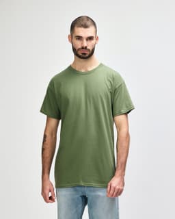 A green Gildan Heavy Cotton adult t-shirt worn by a model standing against a plain background.