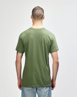 A man wearing a plain olive green Gildan Heavy Cotton Adult T-Shirt, viewed from the back. The shirt has a logo.