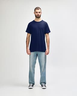 A navy Gildan Heavy Cotton adult T-shirt displayed on a model wearing black jeans and sneakers, with a logo present.