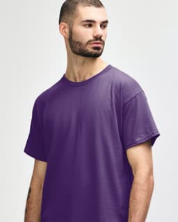 A purple Gildan Heavy Cotton adult t-shirt, displayed on a model with hands behind their back.