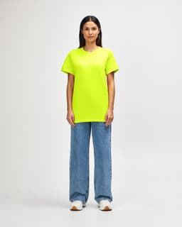 A man stands wearing a bright yellow Gildan Heavy Cotton Adult T-Shirt and black jeans, with sneakers.