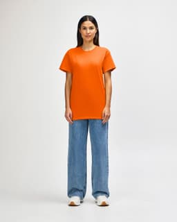 An orange Gildan Heavy Cotton adult T-shirt worn by a standing male model, paired with black jeans and sneakers.