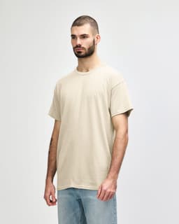 A light beige adult t-shirt in a casual style, featuring a crew neck and short sleeves. It has a branding logo on the tag.