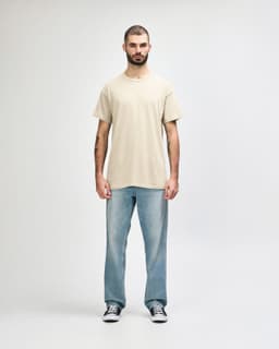 A light beige Gildan Heavy Cotton Adult T-Shirt worn by a male model, paired with black jeans and sneakers.