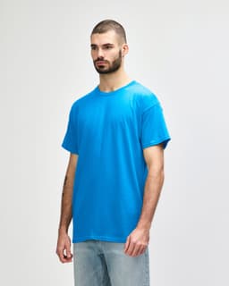 A model wearing a bright blue Gildan Heavy Cotton adult T-shirt, featuring a plain design and a logo on the chest.