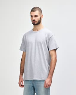 A grey Gildan Heavy Cotton adult T-shirt displayed on a model, featuring a simple design and a relaxed fit.