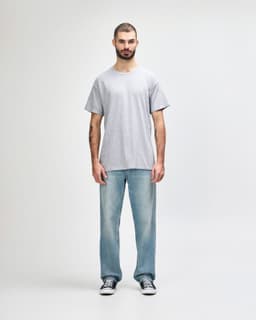 A grey Gildan Heavy Cotton adult T-shirt displayed on a male model wearing black pants and sneakers.