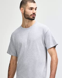 A grey Gildan Heavy Cotton Adult T-Shirt displayed on a model, featuring a simple design and a logo.