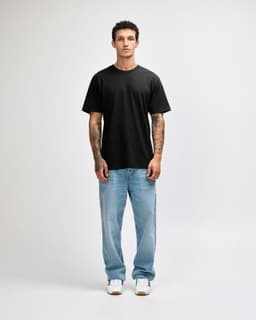 A black unisex short sleeve T-shirt displayed on a model wearing light blue jeans and sneakers.