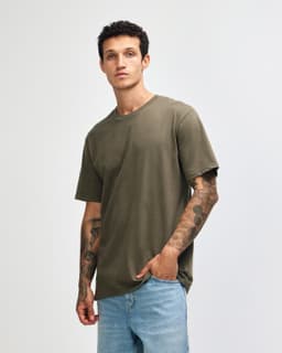 A green unisex short sleeve T-shirt displayed on a model, featuring a simple design and relaxed fit.