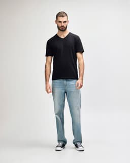 A black Gildan Softstyle adult v-neck t-shirt displayed on a model, paired with black jeans and sneakers.
