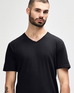 A black Gildan Softstyle adult v-neck t-shirt worn by a model standing with hands behind their back.