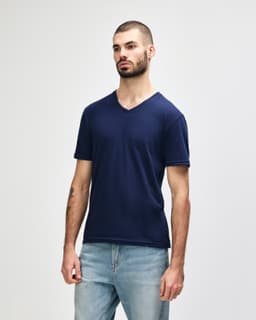 A navy Gildan Softstyle adult v-neck t-shirt on a model, featuring a logo on the shirt.