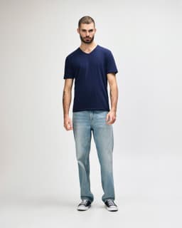 A navy blue Gildan Softstyle adult V-neck T-shirt displayed on a model, paired with black jeans and sneakers.