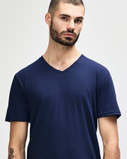 A navy Gildan Softstyle adult v-neck t-shirt displayed on a model with short sleeves. The garment has a logo.