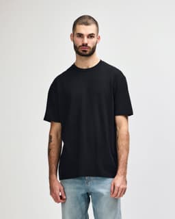 A black Gildan Softstyle adult midweight T-shirt displayed on a model, featuring a simple design and no visible logo.