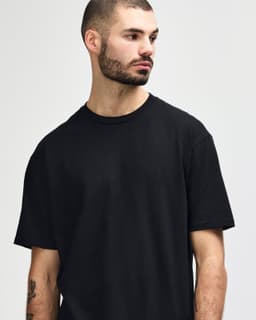 A black Gildan Softstyle adult midweight T-shirt displayed on a model, featuring a simple design and relaxed fit.