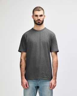 A grey Gildan Softstyle adult midweight T-shirt displayed on a male model, featuring a simple design and a logo.