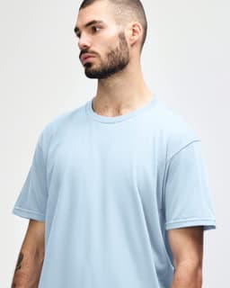 A men’s midweight T-shirt in light blue, featuring short sleeves and a round neckline. It has a small logo.