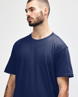A model wearing a navy blue Gildan Softstyle Adult Midweight T-Shirt. The shirt has a round neckline and short sleeves.