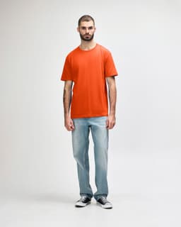 An orange Gildan Softstyle adult midweight T-shirt worn by a model with denim jeans and white shoes.