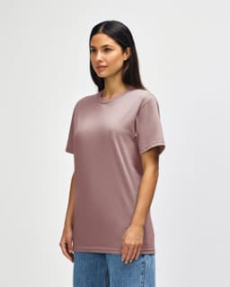 A midweight adult t-shirt in a muted pink colour, featuring a crew neckline and short sleeves. The model stands against a plain background.