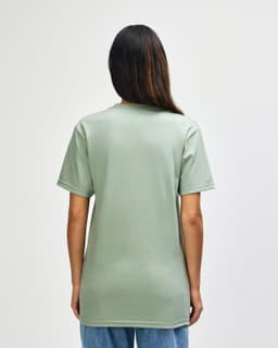 A man wearing a green Gildan Softstyle Adult Midweight T-Shirt, viewed from the back. The shirt has a logo.