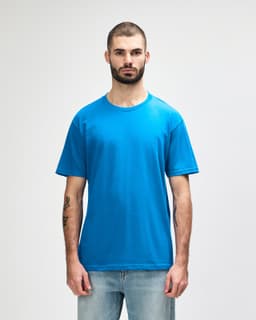 A model wearing a bright blue Gildan Softstyle adult midweight t-shirt, featuring a simple design and a logo.