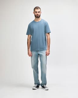 A light blue Gildan Softstyle adult midweight T-shirt displayed on a male model wearing light jeans.