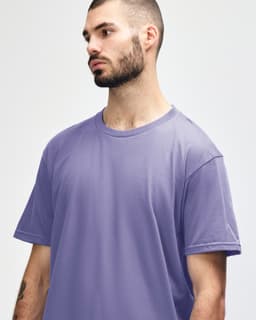 A purple Gildan Softstyle adult midweight T-shirt displayed on a model, featuring a logo on the chest.