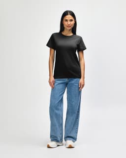 A black Gildan Softstyle ladies midweight T-shirt paired with blue jeans and white sneakers, featuring a logo.