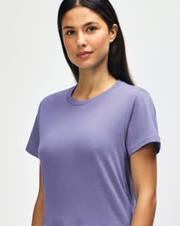 A model wears a light purple Gildan Softstyle ladies midweight T-shirt. The shirt has a round neckline and short sleeves.