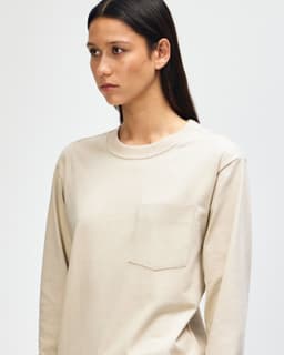 A model wearing a beige American Apparel Super Heavyweight T-Shirt with a pocket and a branded logo.