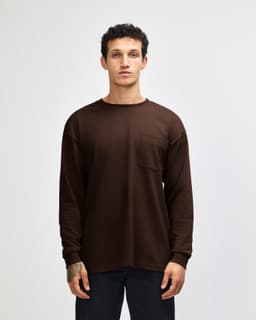 A brown Super Heavyweight T-shirt featuring long sleeves and a chest pocket, with a simple logo on the side.