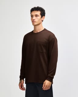 A brown long-sleeve t-shirt featuring a pocket and a branding logo.