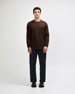 A model wearing a brown long-sleeve shirt with a pocket and green cargo pants, paired with sneakers.
