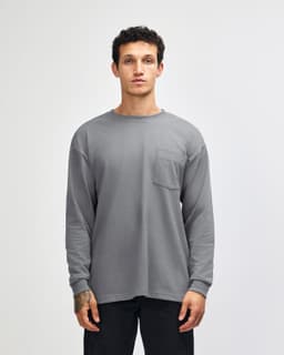 A grey long-sleeve t-shirt with a chest pocket, featuring a logo on the label.