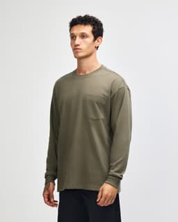A long-sleeve, olive green t-shirt featuring a pocket and a logo, modelled by a young man.