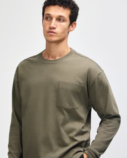 A model wearing an olive green American Apparel Super Heavyweight T-Shirt with a pocket. The shirt features long sleeves.