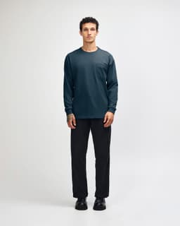A model wears a navy long-sleeve T-shirt with a pocket, paired with olive green cargo pants and sneakers.