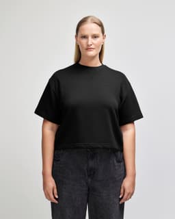 A black, mid-length boxy top for women made of French terry material, featuring a relaxed fit and short sleeves.