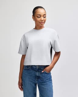 A grey women's mid-length boxy top with short sleeves, featuring a relaxed fit and a brand logo.