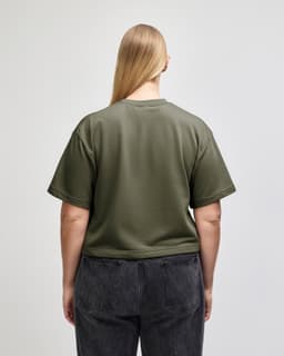 A mid-length boxy top in olive green, featuring short sleeves and a relaxed fit, with a logo present.