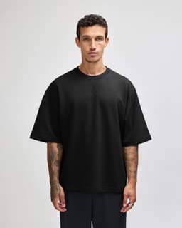 A black oversized boxy top with short sleeves. The top has a simple design and features a branding logo.