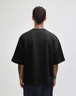 A black oversized boxy top made from French terry fabric, featuring a simple design and a logo on the back.