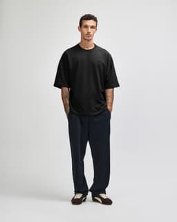 A black oversized boxy top worn with blue denim jeans, featuring a casual, relaxed fit and a logo.