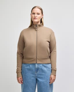 A women's full-zip jacket in a light brown colour, featuring a high collar and fitted cuffs. Includes a logo.