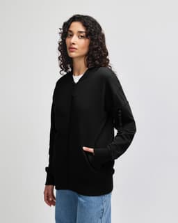A black unisex bomber jacket featuring a front zipper and a logo on the sleeve.